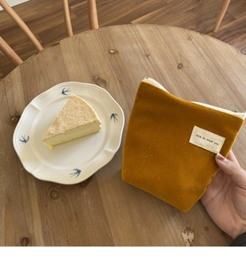 Mini fluwelen zakje in mosterdgeel met ritssluiting op een gezellige houten tafel