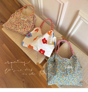 Detailed close-up of three floral canvas tote bags with woven rope handles in home setting