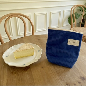 Detailopname van een blauwe corduroy make-uptas met rits op een houten tafel
