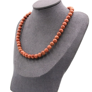 Polished golden sand stone round bead necklace displayed on a dark grey jewelry bust