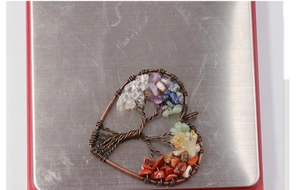 Macro view of handmade tree of life heart pendant with copper wire and colorful gemstones