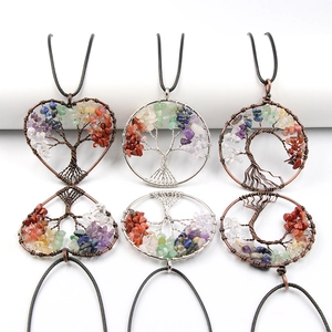Handmade copper wire tree of life pendants with natural crystal stones on white pedestals