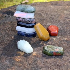 Polished natural crystal coffin stones including lapis and obsidian on dark rock