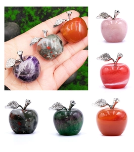 Detailed view of apple-shaped natural gemstones with engraved silver leaf and crystal inlay