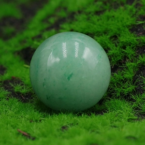 Polished Green Aventurine quartz crystal ball on a natural mossy decorative surface