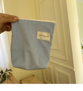 Handheld blauw corduroy mini make-up tasje met ritssluiting en een tekstlabel erop