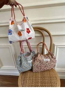 Detailed macro view of floral canvas tote bags with thick woven rope handles and woven labels