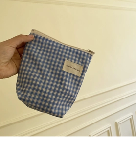 Detail van blauw geruit katoenen minizakje met ritssluiting en tekstlabel erop
