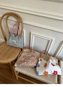 Detailed view of floral canvas tote bags with colorful braided rope handles and woven labels
