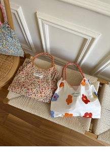 Detail of floral canvas tote bags with woven rope handles on a woven chair
