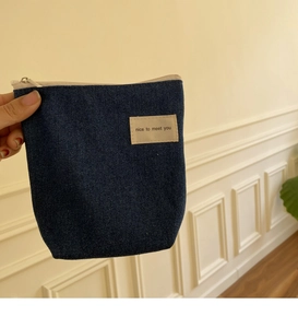 Detailopname van een blauwe denim mini make-up tas met nice to meet you label