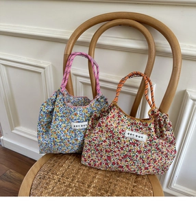 Detail of floral canvas tote bags with contrast rope handles on a vintage chair
