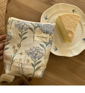 Detail van bloemen canvas make-up tas met rits op een houten tafel met een keramiek bord