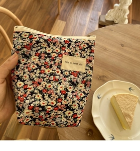 Detail van gebloemd katoenen make-up tasje met beige label op een houten achtergrond