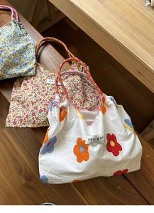Detail of floral canvas tote bags with rope handles on a wooden bench in natural light