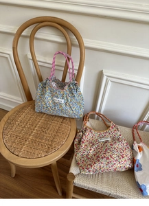 Close-up of floral tote bags with colorful braided handles on a wooden chair