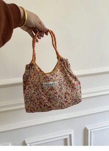 Detail of floral canvas tote bag featuring orange braided rope handles and fabric label