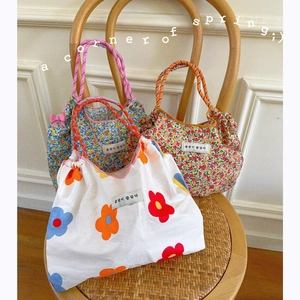 Floral canvas tote bags with drawstring closure and colorful rope handles on a vintage chair