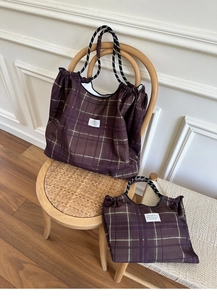 Detail view of purple checkered tote bags with rope handles and decorative woven label