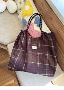 Detail of the vintage plaid tote bag featuring a white fabric label and sturdy rope handles