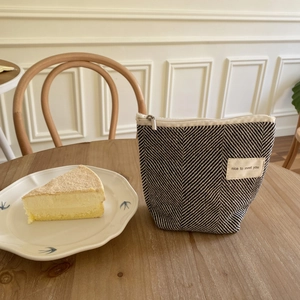 Mini katoenen cosmetische tas met visgraatpatroon en rits op houten tafelblad decor