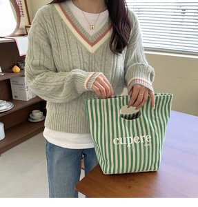 Dettaglio della borsa tote in tela a righe bianche e verdi con manico rotondo ritagliato
