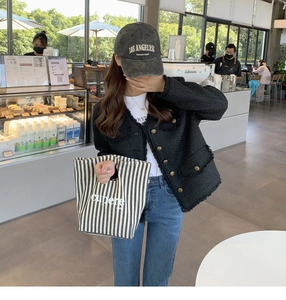 Dettaglio di una borsa in tela abbinata a una giacca in tweed e un cappellino sportivo
