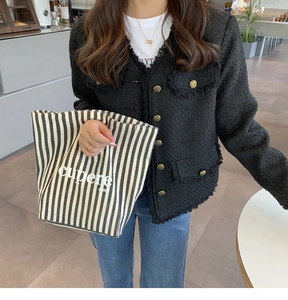 Dettaglio di una borsa tote in tela a righe bianche e nere con giacca in tweed