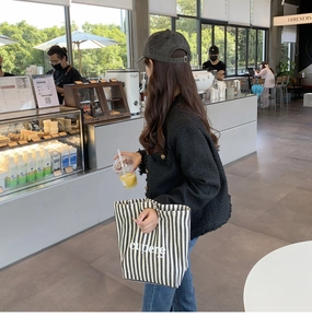 Primo piano di una borsa tote in tela a righe bianche e nere con scritte in un caffè
