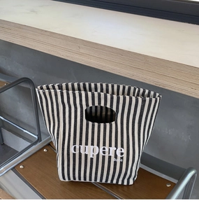 Vista dettagliata della borsa pranzo in tela a righe con manico cavo e stampa di lettere