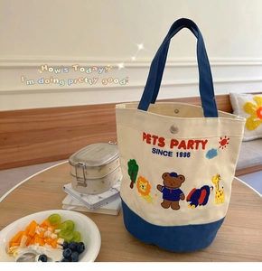 Detail of canvas tote bag with Pets Party embroidery and animals on wooden table