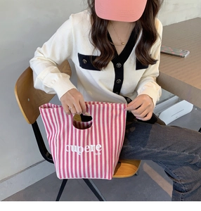Dettaglio della borsa tote in tela a righe bianche e rosa con scritta Cupere Dune casual