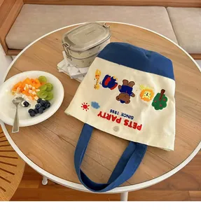 Detailed close-up of navy and beige canvas bag with animal embroidery on wooden table