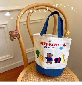 Detail of canvas tote bag with colorful animal embroidery and navy blue bottom contrast