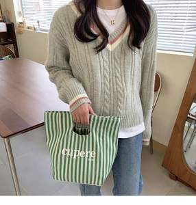 Dettaglio della borsa tote in tela a righe bianche e verdi con scritte in stile casual