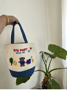 Detail of canvas lunch bag featuring animal embroidery and silver metal snap button