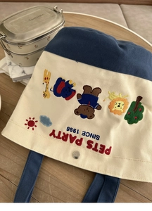 Detail of animal embroidery and metal snap button on blue-white canvas lunch tote bag