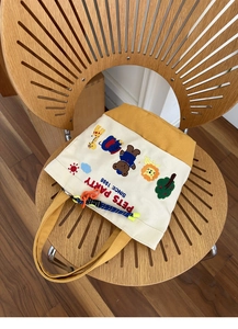 Close-up of yellow and white canvas bag with colorful animal embroidery and PETS PARTY text