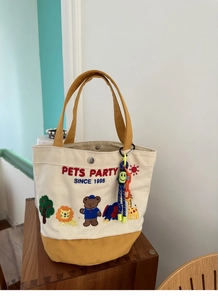 Detail of canvas lunch bag featuring animal forest embroidery and a smiley face charm
