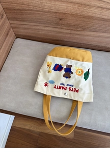 Detail of canvas bag showing cute animal embroidery and metal snap button closure