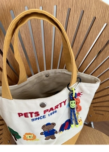 Detail of canvas tote bag featuring animal embroidery and yellow webbing handles on chair