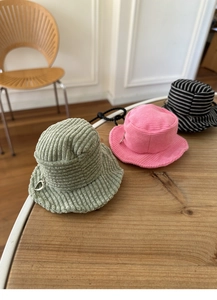 Mini corduroy bucket hat coin purses in green and pink with heart charms on a wood table