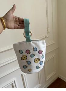 Dettaglio della borsa a secchiello in tela floreale con manici in legno e fiori colorati