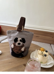 Dettaglio della borsa a secchiello in tela con manico in legno e cucciolo di peluche 3D