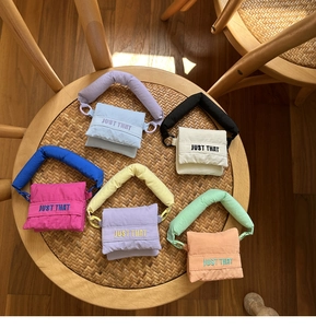 Detailed view of colorful puffed mini pouches in blue, purple, and green on a rattan chair