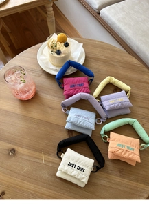 Assorted colorful quilted mini crossbody bags with JUST THAT embroidery on a table