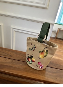 Dettaglio del manico con anello in legno su borsa in tela con illustrazioni di frutta