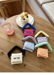 Detailed view of colorful quilted nylon mini bags with JUST THAT embroidery on a table