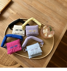 Macro view of four colorful puffy mini handbags on a wooden tray with embroidery detail