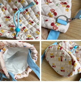 Detail of pink quilted bucket bag with cherry bear prints and blue drawstring strap